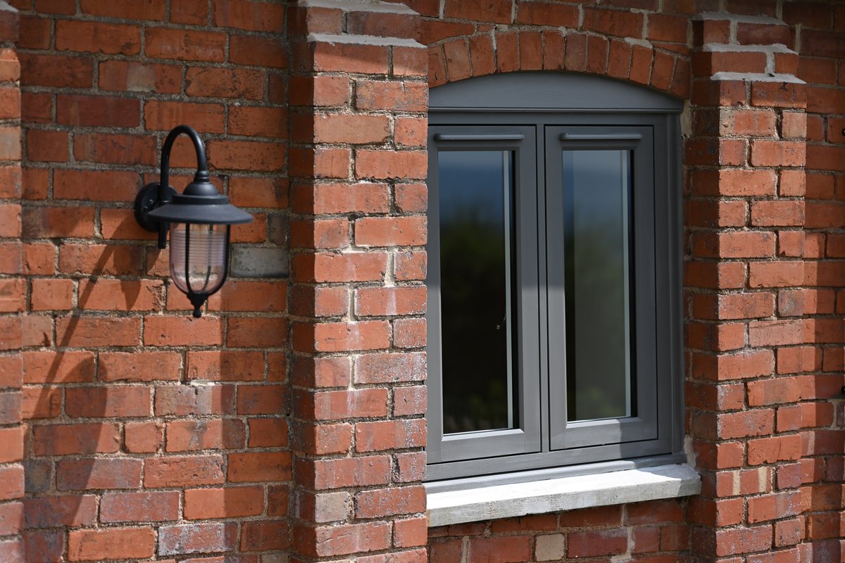 Residence 9 anthracite grey flush window detail on a red brick home