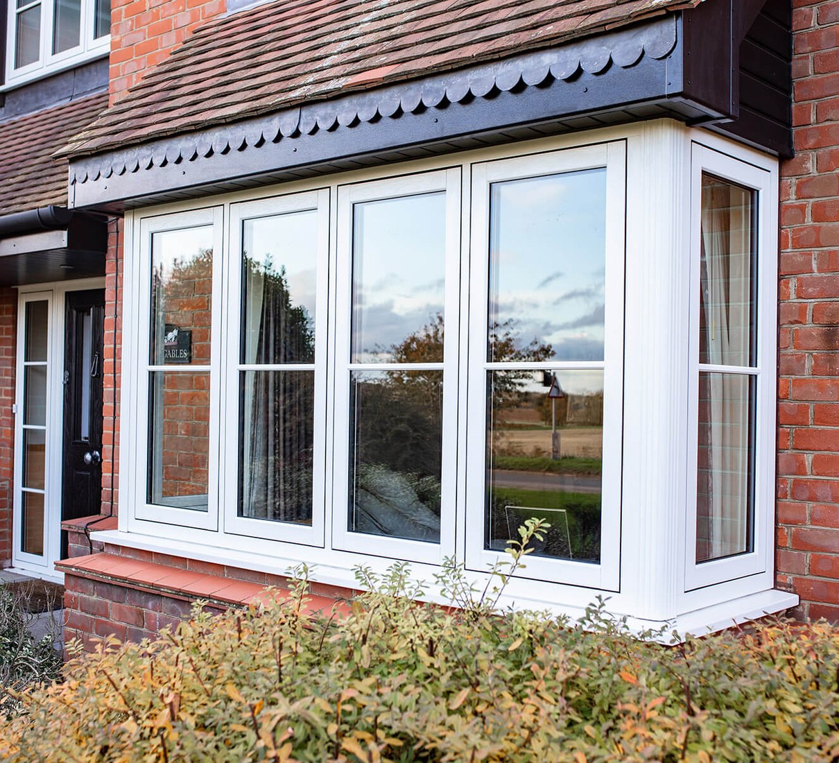 VEKA / Timeless white flush casement bay window on a red brick home